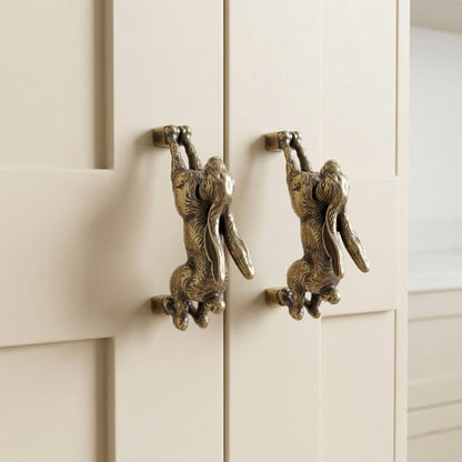 Hopping hare handles in antique brass on two cabinet doors