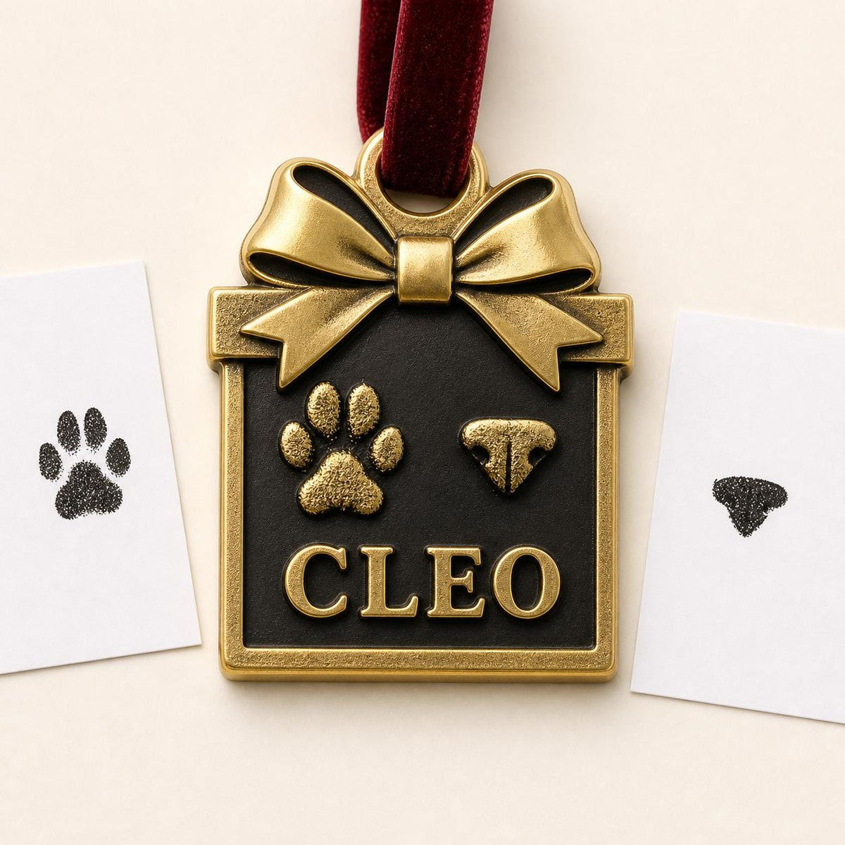 Antique brass box-shaped pet ornament with a bow, raised paw print, nose print and CLEO, beside the ink print cards