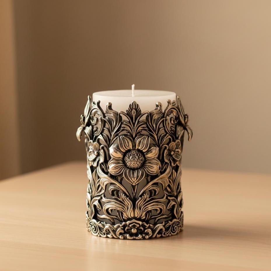Antique brass floral pillar candle holder with raised flowers and scrolls around a white candle, on a wooden table