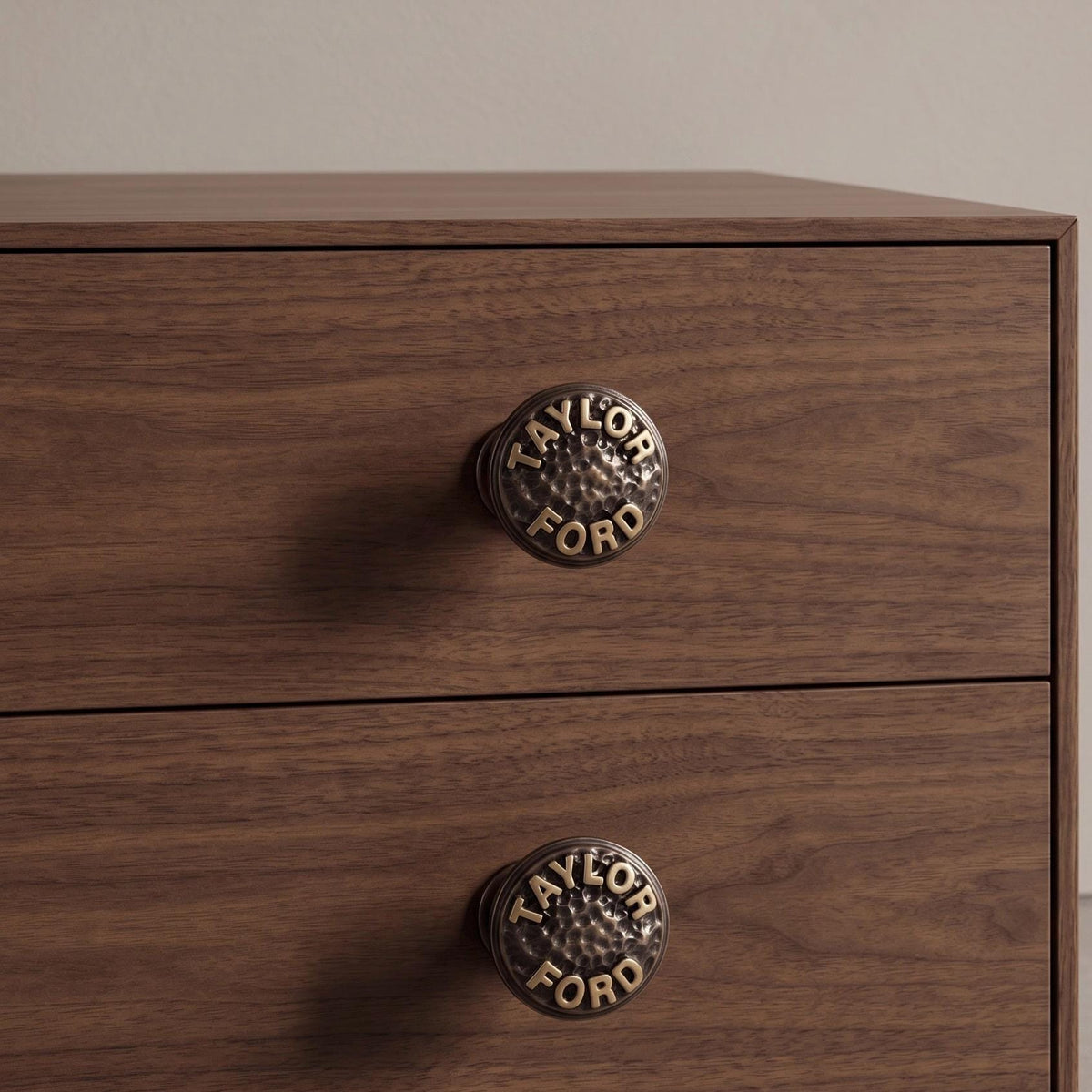 Two TAYLOR FORD name knobs fitted on dark wood drawers