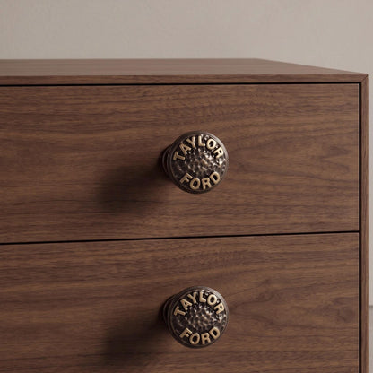 Two TAYLOR FORD name knobs fitted on dark wood drawers