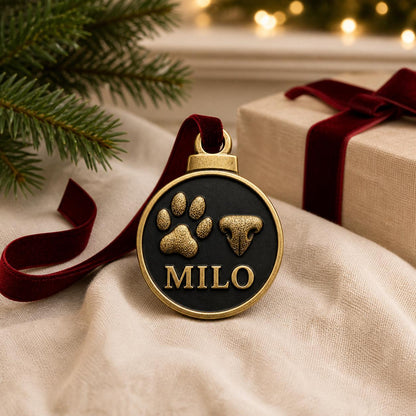 Round pet print ornament resting on a cream throw beside a box tied with red velvet ribbon