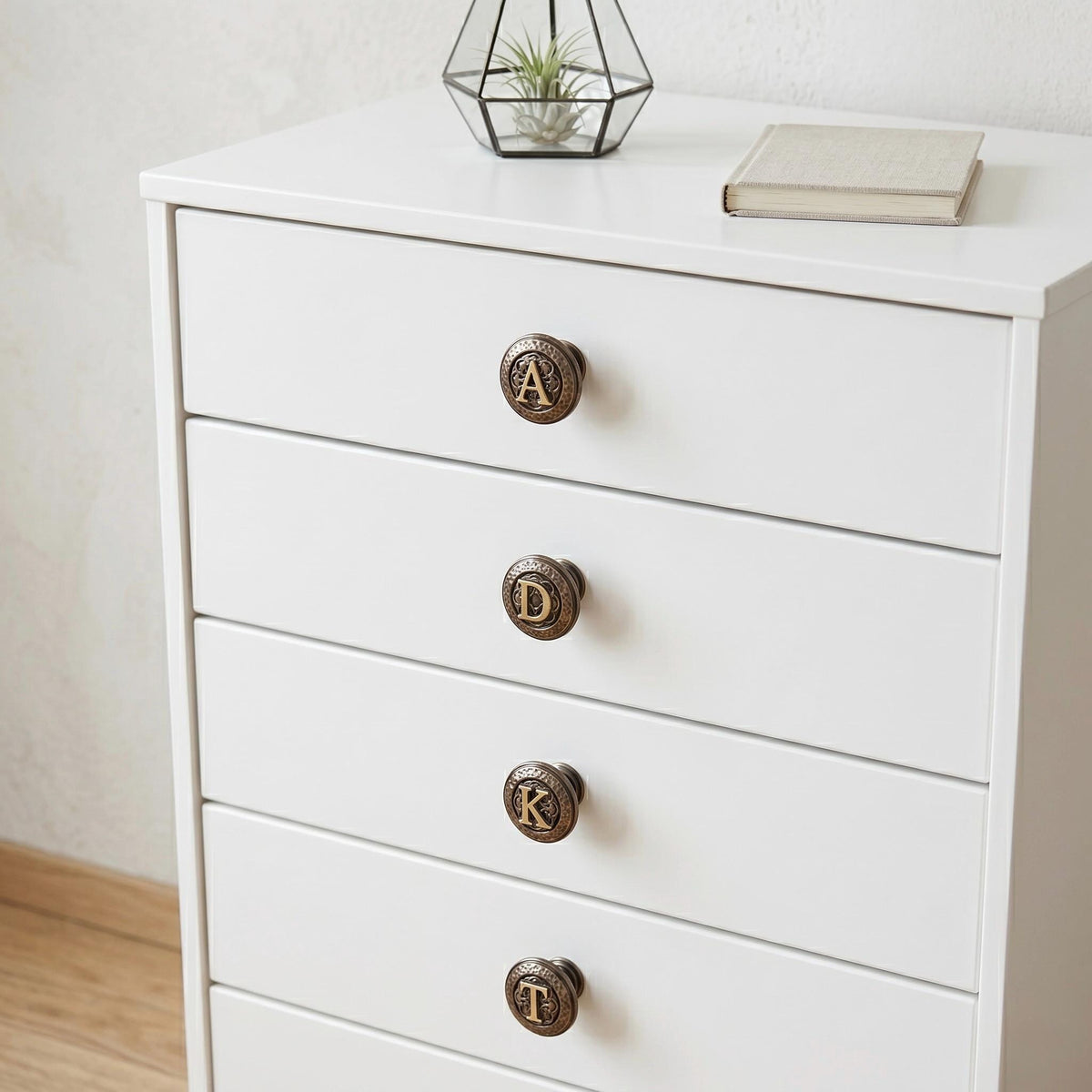 Initial knobs reading A, D, K and T on a white chest of drawers
