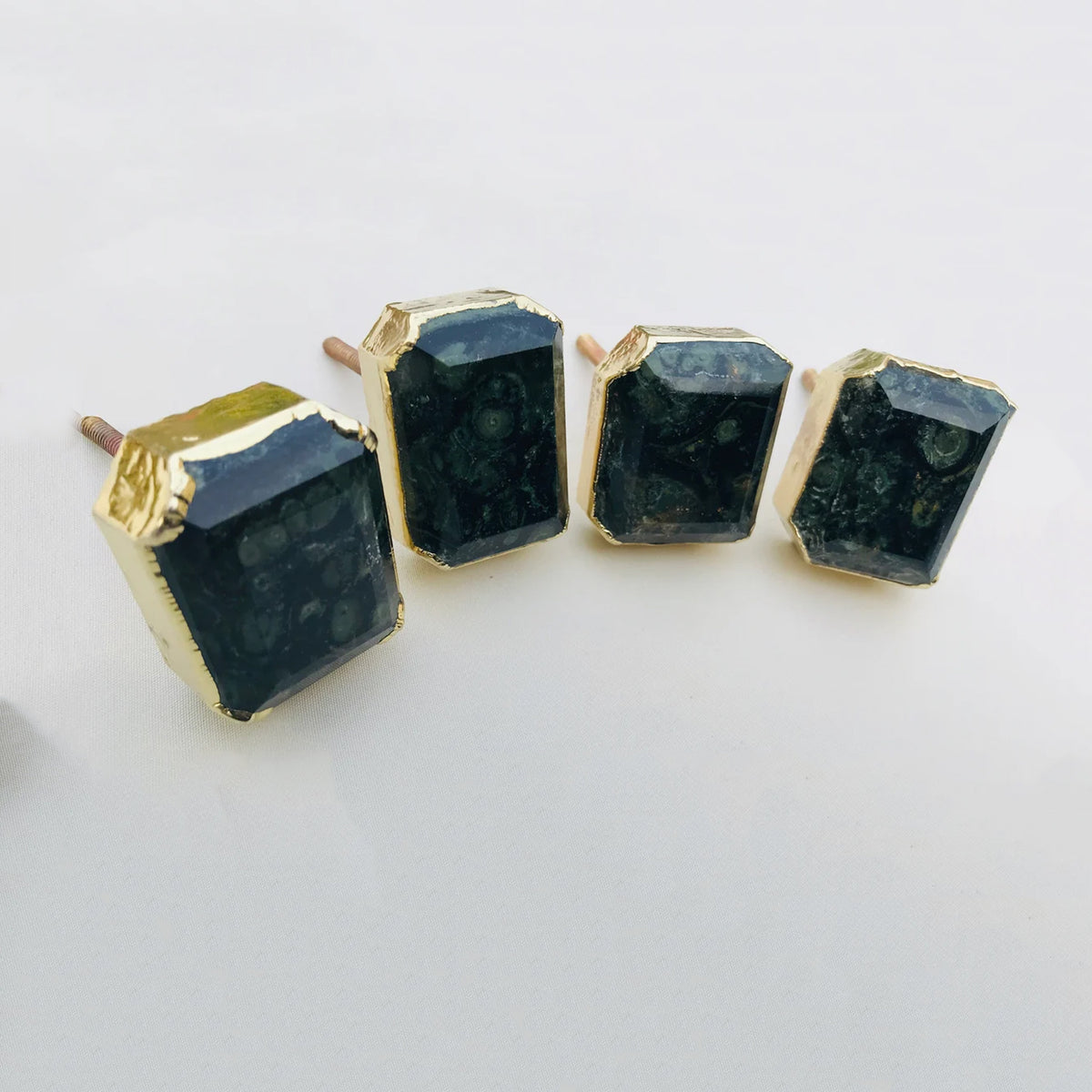 Four rectangular faceted hematite cabinet knobs in gilded collars