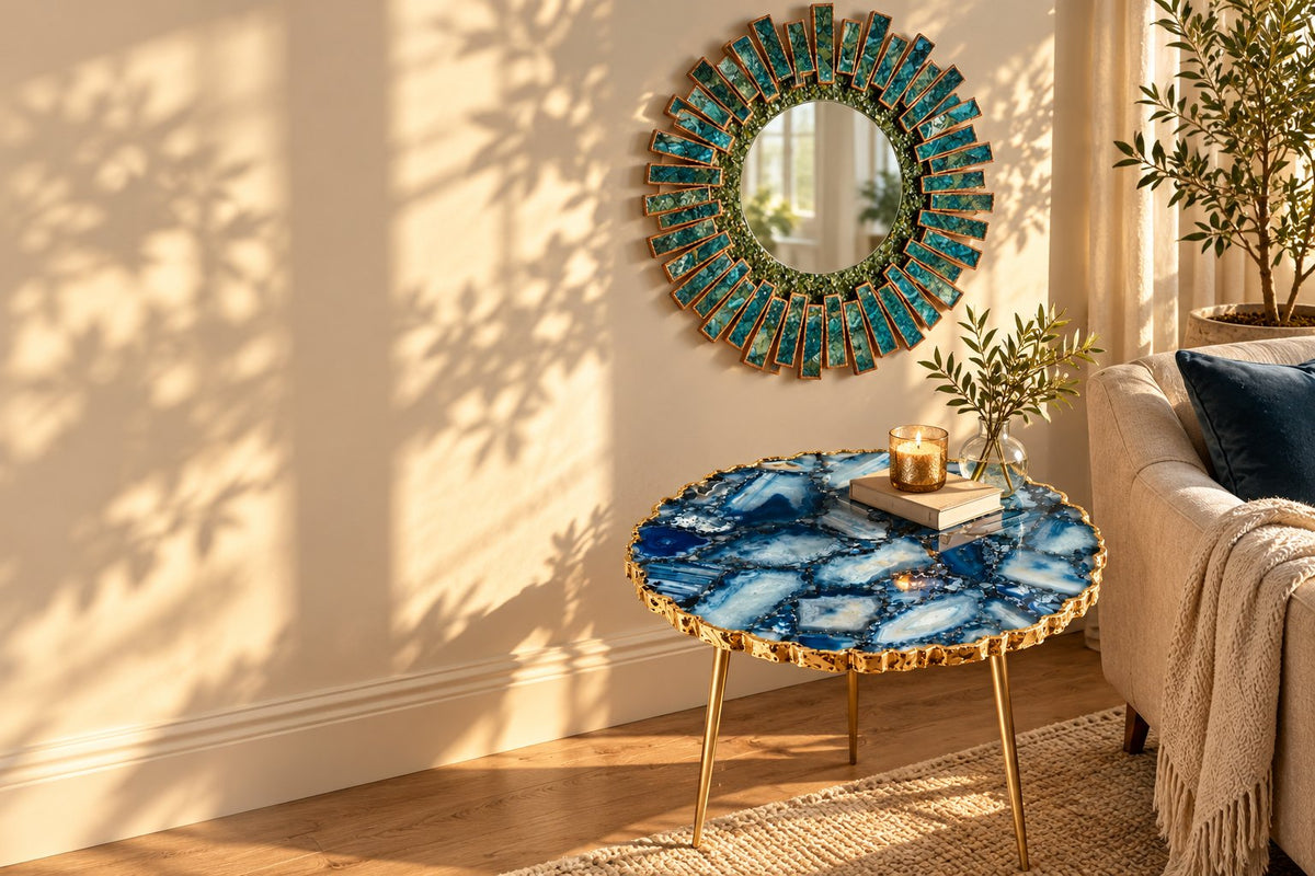 Blue agate side table with gold legs beneath a teal starburst mirror in a sunlit living room